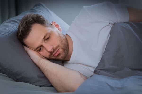 Anxiety and Sleep Young man seeks sleep while anxiety keeps him awake in bed at night