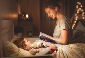 stock photo of a mother and child daughter reading book in bed before going to sleep