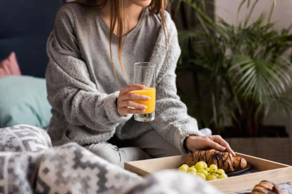 Do You Make These Four Common Bedtime Food Mistakes? young woman makes common bedtime food mistakes while eating in bed