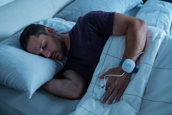 At-Home Sleep Apnea Tests Person using a home sleep test in bed