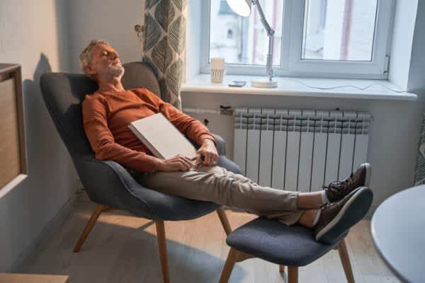 Napping: How Dozing During the Day Affects Your Sleep at Night stock photo of a man taking a nap with a book in his lap
