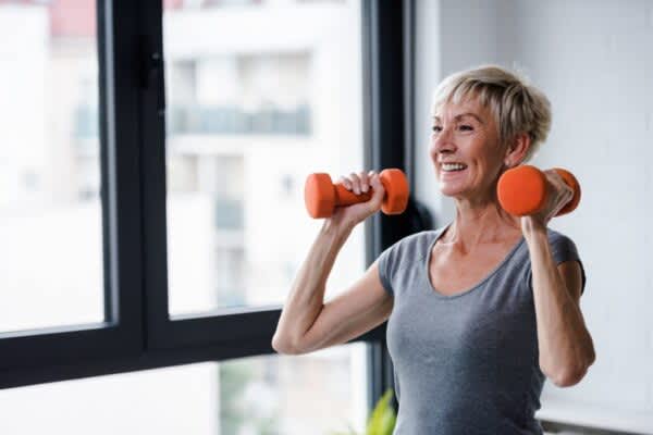 Physical Health: How Your Overall Well-Being Impacts Sleep Smiling senior woman lifitng weights