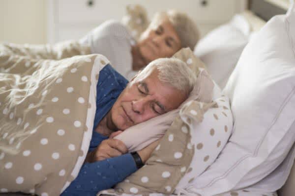 Aging and Sleep: How Much Sleep Do Seniors Need? Senior couple sleeping peacefully in bed.