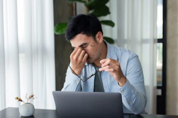How to Reset Your Sleep Schedule stock photo of a tired man rubbing his eyes