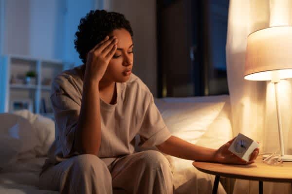 Treatment for Insomnia: Our Guide to Improving Restless Nights stock photo of a woman staring at a clock at night