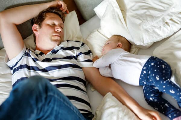 a father and child rest together on a bed