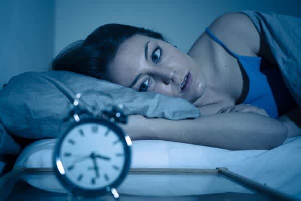 Reasons You Can’t Sleep woman wide awake looking at alarm clock because of reasons you cant sleep