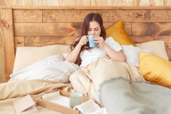 The Best Tea for Sleep: Tasty Choices to Help You Unwind Young woman relaxing in bed with a cup of tea.