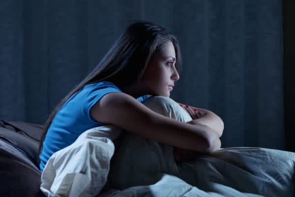 What Causes Insomnia? young woman suffering from insomnia is awake in bed at night